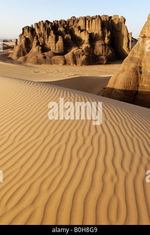 Eroded rock formations rising out of desert sand dunes, ripples in Tin Akachaker, Tassili du Hoggar, Wilaya Tamanrasset, Sahara Stock Photo