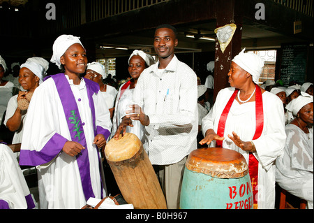 Worshipers singing and playing traditional drums during a church service in Douala, Cameroon, Africa Stock Photo