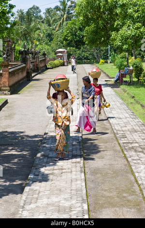 Women carrying basket of fruit on their heads at the entrance to the Pura Meru Temple, Hindu and Muslim temple in Cakra, Lombok Stock Photo
