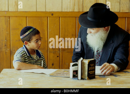 An Orthodox Jewish boy in school with his elderly teacher, USA. Stock Photo