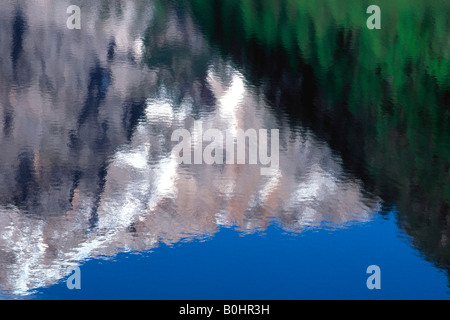 Reflection of green forests and snow capped mountains under blue sky in the Pragser Wildsee lake or Lago di Braies, Bolzano-Boz Stock Photo