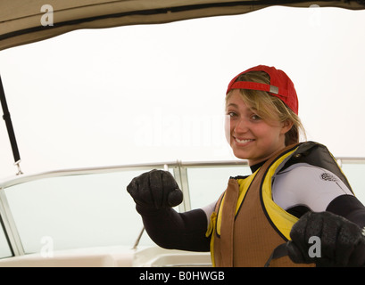 Young woman in a wetsuit and life vest on board a boat. Looking at the camera. Ready for wakeboarding. UK