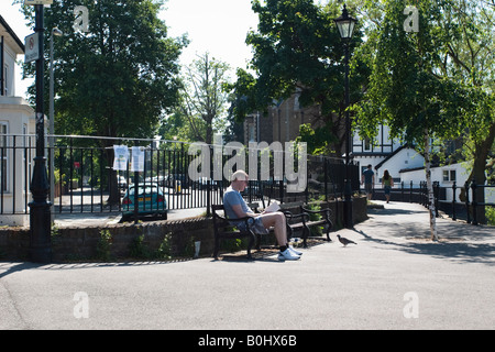 Man sitting on a bench by the side of the Thames at Chiswick strand Stock Photo