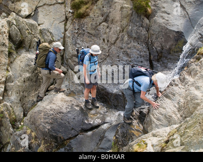 Idwal North Wales UK Group of people walking on path crossing rocky stream in gully in Snowdonia 'National Park' Stock Photo