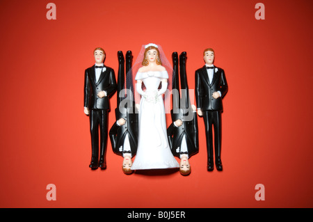 A plastic wedding bride and four men in tuxedos on a red background Stock Photo