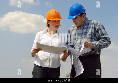 Female investor and site manager discussing building plans over blue sky Stock Photo