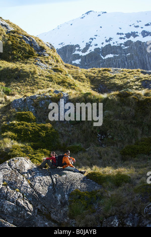 Two hikers sitting on boulders in mountain valley Stock Photo