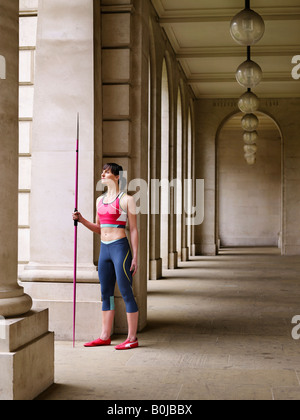 Female athlete holding javelin, standing in portico, portrait Stock Photo