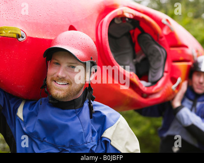 Two men carrying kayak, outdoors, portrait Stock Photo