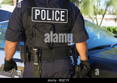 Police officer in bulletproof vest outdoors, back view Stock Photo