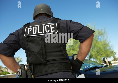 Police officer in bulletproof vest outdoors, back view Stock Photo