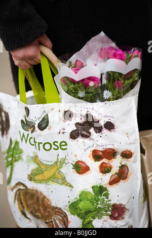 Womans hand holding a Waitrose reusable shopping bag Stock Photo