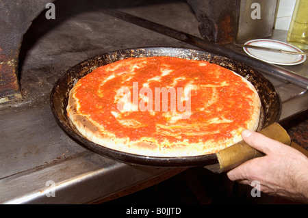 Chef putting Pizza in dish into wood fired oven Stock Photo