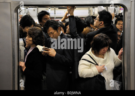 Many commuters in packed railway carriage during rush hour on Tokyo subway in Japan Stock Photo