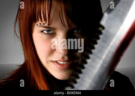 Girl with red hair holding a knife against the camera with an evil smile on her face Studio shot Stock Photo