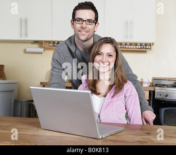 Couple Using Laptop in Kitchen Stock Photo
