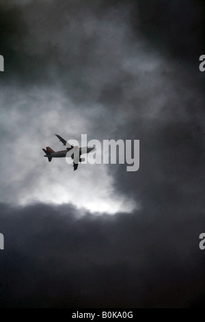 easyjet plane flying through dark clouds in sky Stock Photo