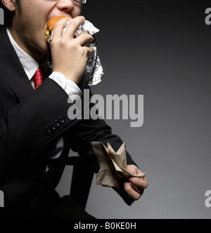 Businessman Eating Hamburger Stock Photo