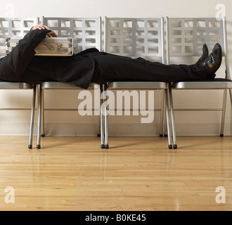 Businessman Sleeping on Folding Chairs Stock Photo