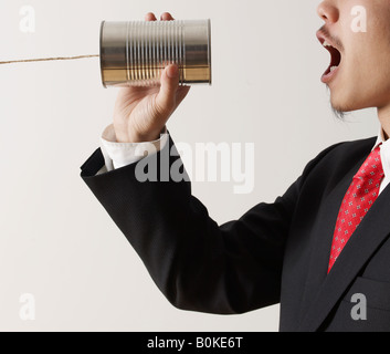 Businessman Shouting into Tin Can Phone Stock Photo