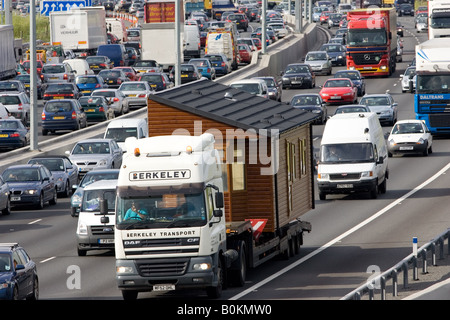 Prefabricated house being transported by road on truck in congested traffic on M25 motorway London United Kingdom Stock Photo