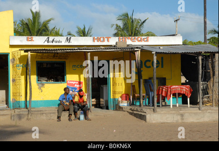 Two boys sitting in the morning sun outside a local store in Tofo Stock Photo