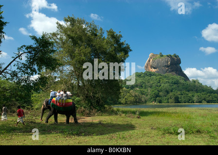 Tourists on elephant ride with Sigiriya rock fortress in background,Sigiriya,Sri Lanka Stock Photo