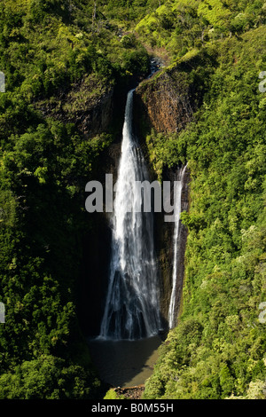 Scenic wide aerial portrait of famous Jurassic Park waterfalls surrounded by green lush trees popular attraction on island of Kauai, Hawaii USA. Stock Photo