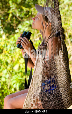 COSTA RICA Woman in hammock bird watching with binoculars Pacuare River Lodge jungle camp Caribbean Slope Stock Photo