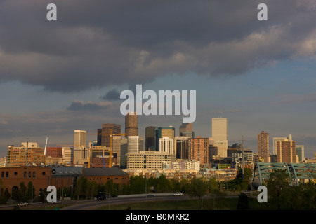 City skyline view from the west of Denver Colorado office buildings highways and skyscrapers at sunset dusk with dark clouds Stock Photo