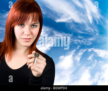 Studio shot of a cute girl with red hair holding keys with a blue sky Stock Photo