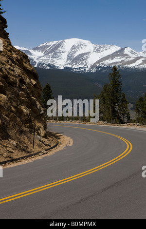 A bend in the Trail Ridge Road reveals snow capped mountains with clear blue sky in Rocky Mountain National Park Colorado USA Stock Photo