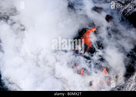 Aerial close view from above bright red hot volcanic lava magma flowing into ocean, rising clouds of steam, coast of Hilo Hawaii, the Big Island, USA Stock Photo