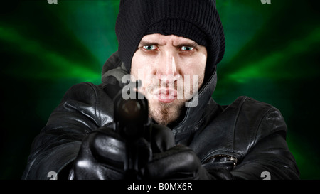 Portrait of an undercover agent or delinquent dressed in black leather and balaclava hat firing handgun in the camera Stock Photo