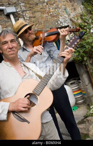 two Folk musicians playing acoustic guitar and fiddle violin  music outdoors, wedding Druidstone Hotel, Pembrokeshire Wales UK Stock Photo