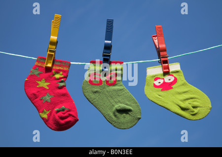 Three different baby socks drying on a clothes line. Stock Photo
