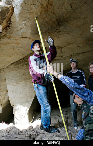 People measuring height while exploring cave at Vaidavas hillfort in Gauja National Park Latvia Stock Photo