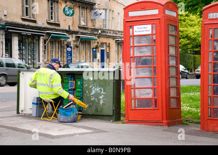 British Telecom engineer at work on a junction box in the city next to old style telephone boxes Stock Photo