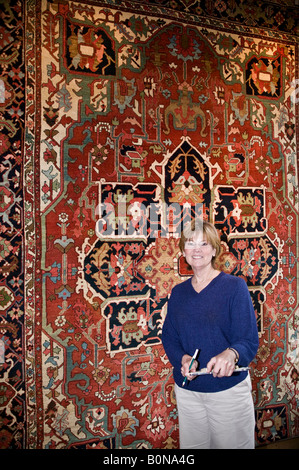 Portrait of female salesperson with antique rug hanging in store, Telluride, Colorado, USA Stock Photo