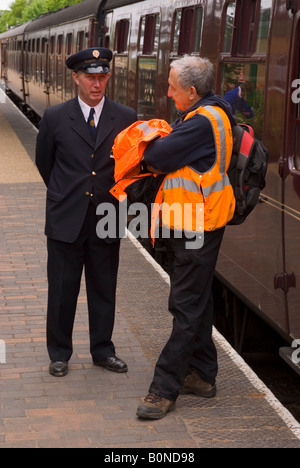 The Station Master Talking To Railway Worker At Holt Station,Norfolk,Uk Stock Photo