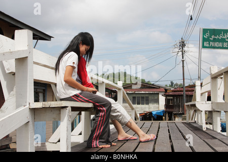 Girls Sitting In Stilt Village Of Kampung Ayer, Brunei Stock Photo