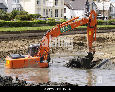 Digger working deep in the mud and water clearing out the bottom of Bude canal, Cornwall, UK Stock Photo