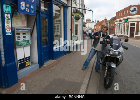 Retro petrol pump UK old fashioned overhead hose man filling up a customers motorbike. Wainfleet All Saints, Lincolnshire England 2000s 2008 Stock Photo