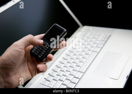 Mobile Phone on a silver laptop. Using the mobile Phone Stock Photo