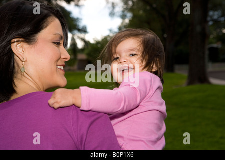 happy Navajo toddler being held by her mother at a park Stock Photo