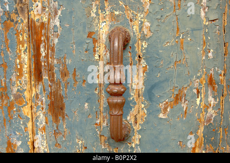 Peeling blue paint on an old wooden door with rusted handle Stock Photo