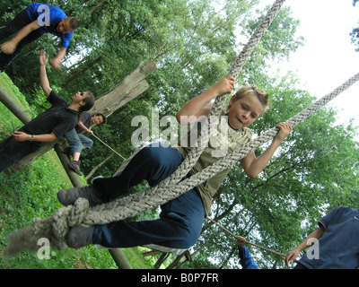 boy student holding on to climbing ropes at school camp Stock Photo