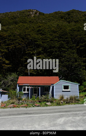 An old grey shack with orange roof in set against a mountain in Arthurs Pass village, New Zealand Stock Photo