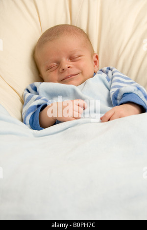 Smile on Lips of Grinning Newborn Baby Boy Joshua Kailas Hudson Aged 20 days as he Sleeps in Beanbag Stock Photo