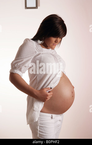 36 week pregnant teenage woman looking at her exposed stomach . Stock Photo